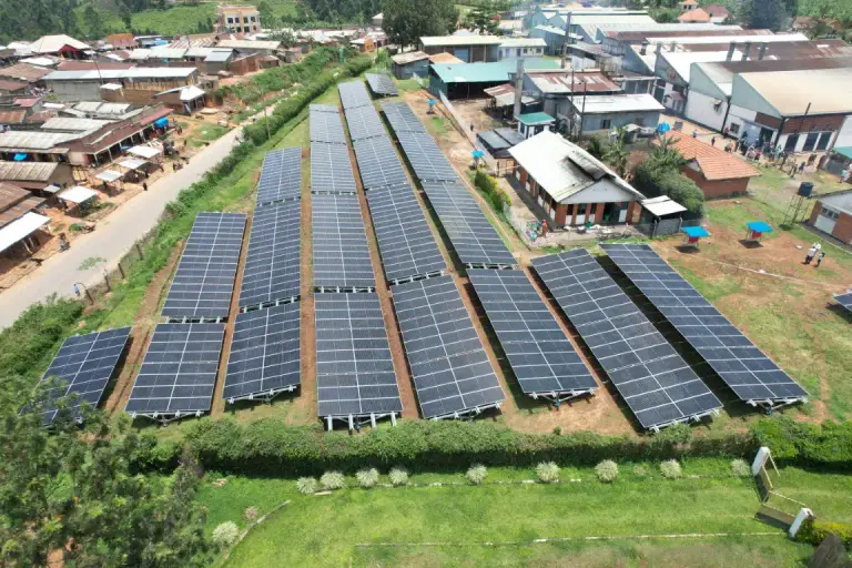 Aerial view of a ground-mounted solar array beside industrial buildings